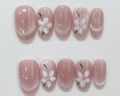 Pink nail art with white floral designs on a light gray background