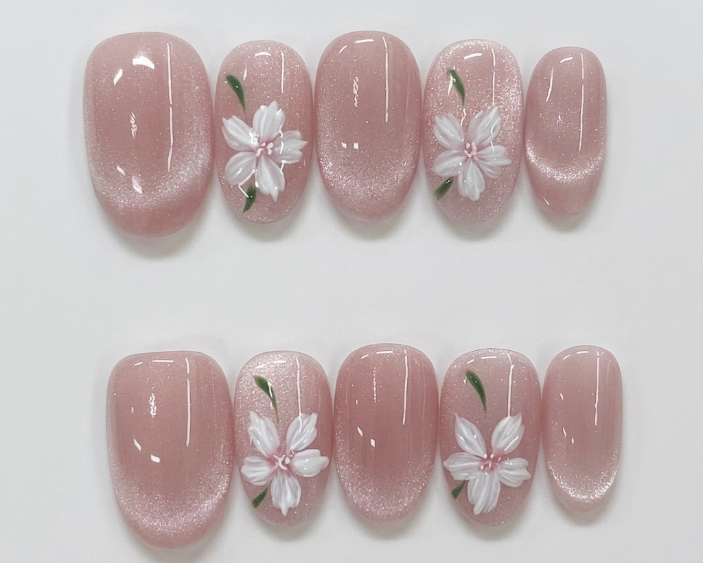 Pink nail art with white floral designs on a light gray background